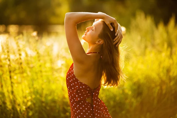 Счастливая длинноволосая женщина на закате в поле — стоковое фото