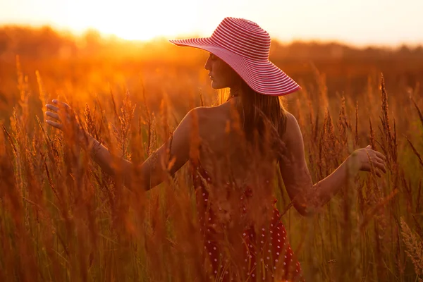 Glad kvinna i en hatt av ängen gräset — Stockfoto