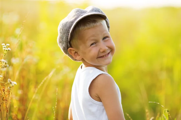 Ευτυχισμένος χαμογελαστό αγόρι σε ένα γκρι κάλυμμα — Φωτογραφία Αρχείου