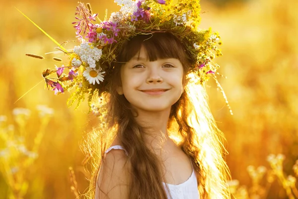 Glückliches süßes Mädchen trägt einen Blumenkranz — Stockfoto