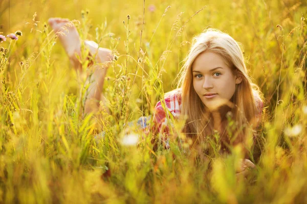 Gelukkig meisje liggen onder de wilde bloemen — Stockfoto