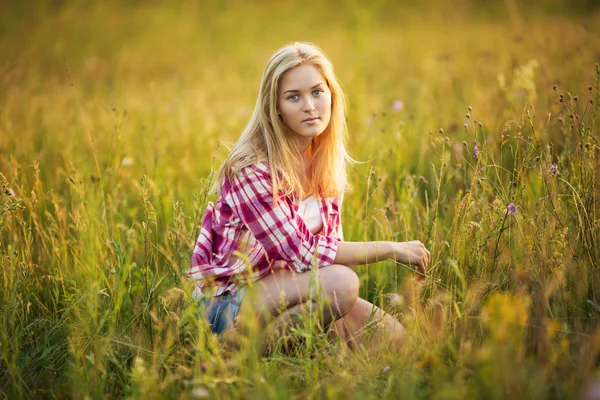 Krásná dívka sedí v trávě — Stock fotografie