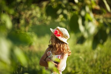 Şapkalı kız ve bitki örtüsü arasında duruyor