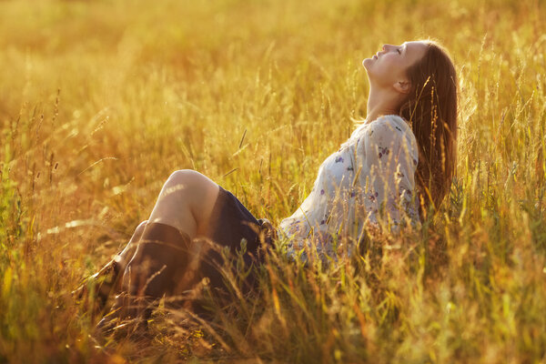Счастливая женщина сидит в траве
