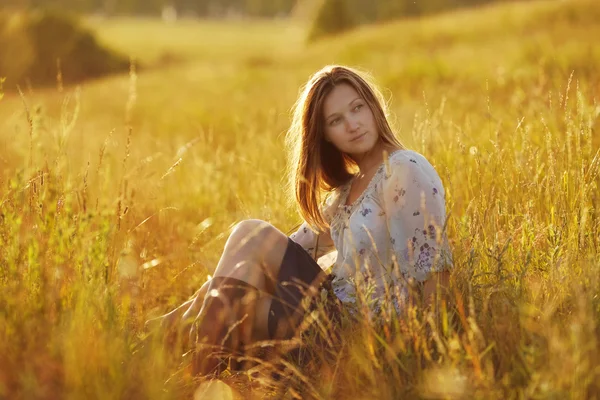 Beautiful woman sitting in a meadow — Stock Photo, Image