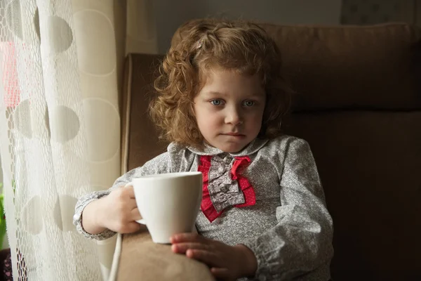 Pequeña niña pensativa con una taza — Foto de Stock