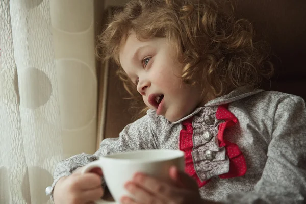 Красивая кудрявая маленькая девочка с чашкой — стоковое фото