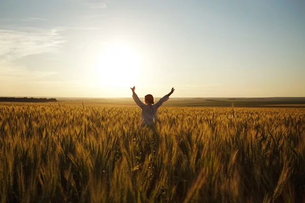 Frau steht in einem Feld aus reifem Weizen — Stockfoto