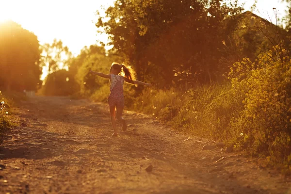 Menina feliz correndo ao longo de uma estrada rural Fotografias De Stock Royalty-Free