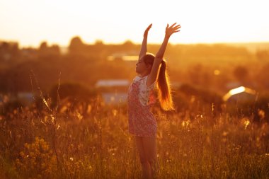 Happy girl in a field on summer evening