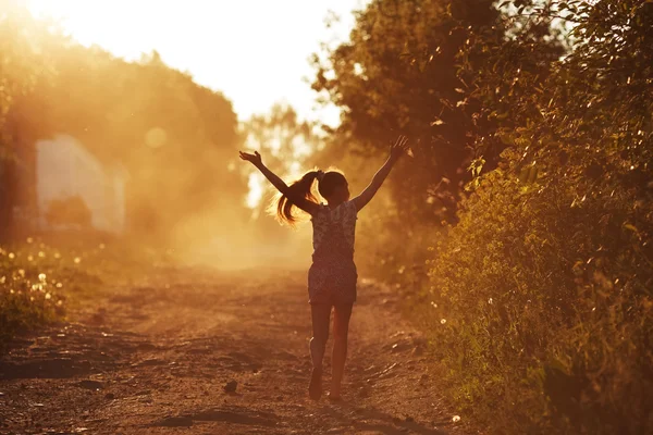 Menina feliz correndo em uma estrada empoeirada — Fotografia de Stock