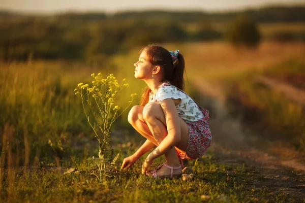 Girl inhales aroma of a wildflower — Zdjęcie stockowe