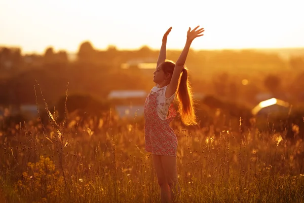 Glückliches Mädchen auf einem Feld an einem Sommerabend — Stockfoto