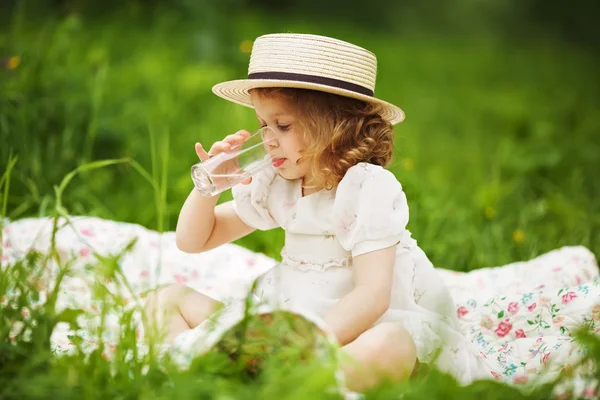 Kleines Mädchen sitzt und trinkt — Stockfoto