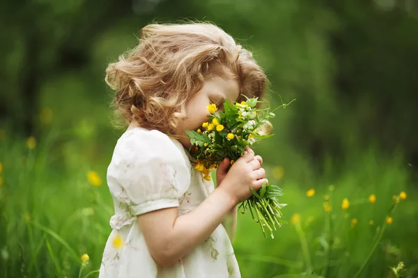 Little girl smelling a bouquet of flowers