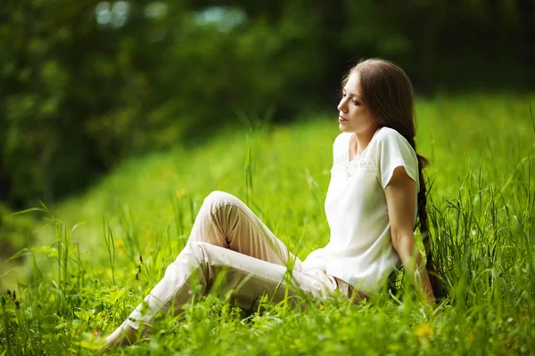 Zamyślony kobieta siedzi na trawie — Zdjęcie stockowe
