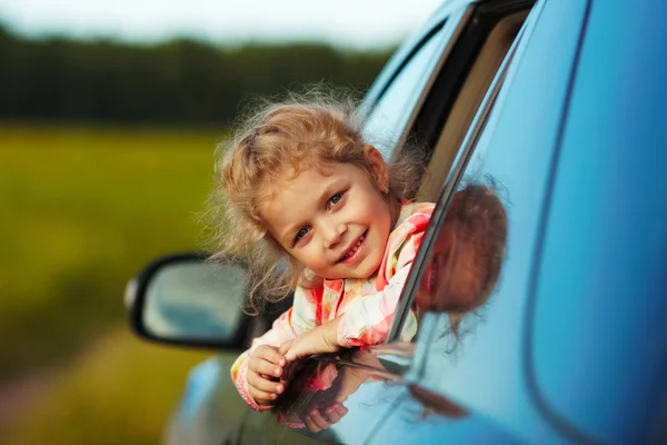 Happy girl looks out the car window — Stock Photo, Image