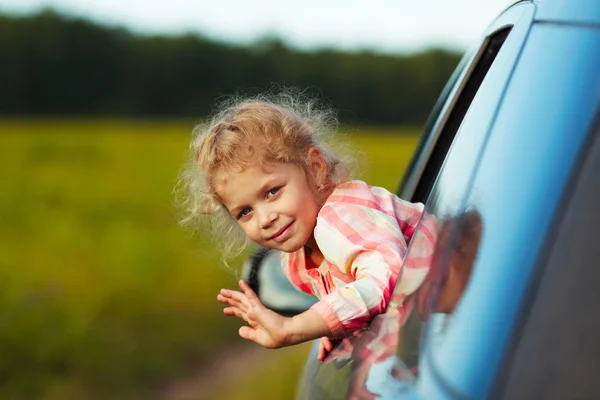 Little girl waving from car window — Stock Photo, Image