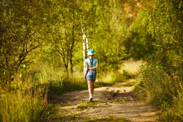 Girl in a hat walks through the birch forest — Stock Photo, Image