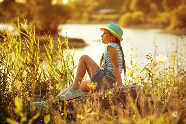 Girl sitting on the river bank — Stock Photo, Image