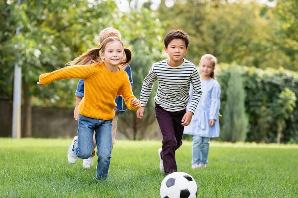 Glada Multietniska Barn Spelar Fotboll Nära Vänner Suddig Bakgrund Parken — Stockfoto