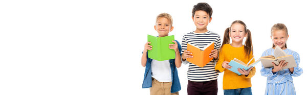 Cheerful multicultural kids holding books isolated on white, banner 