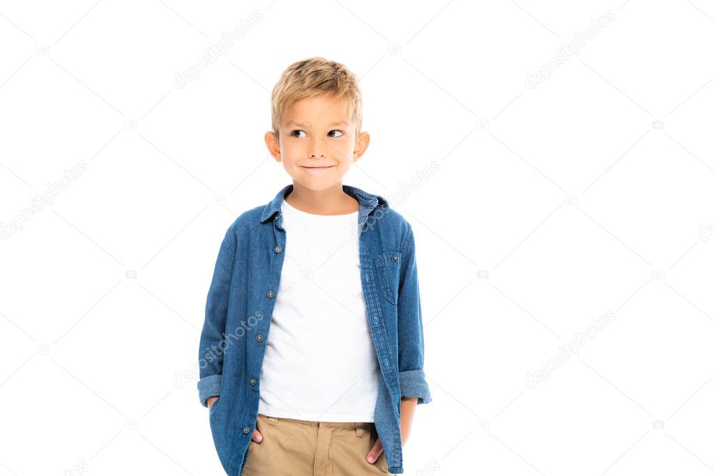 Cheerful boy with hands in pockets of pants looking away isolated on white