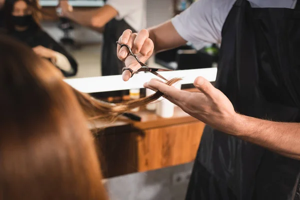 前景にクライアントの髪を切断美容師のクロップドビュー — ストック写真
