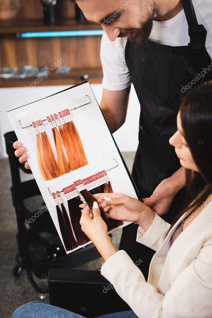 hairdresser showing hair colors palette to young woman on blurred foreground