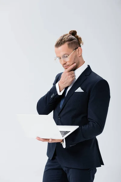 Σκεπτικός Νεαρός Επιχειρηματίας Κοστούμι Και Γυαλιά Φορητό Υπολογιστή Απομονωμένο Λευκό — Φωτογραφία Αρχείου