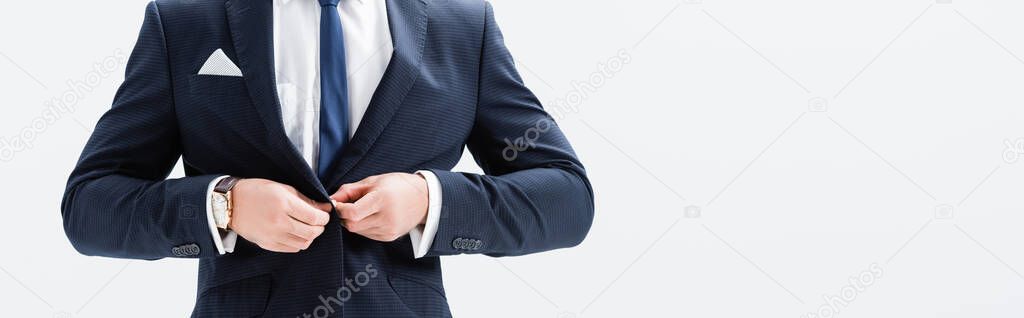 cropped view of young businessman in suit buttoning blazer isolated on white, banner