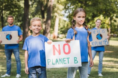 Çocuğun elinde B gezegeni yazıtları olmayan afişleri bulanık arka plan, ekoloji konsepti olan ailelerin yanında.