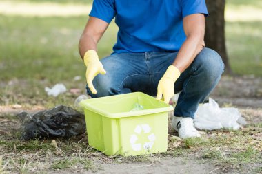 Geri dönüşüm amblemiyle plastik atık toplayan adamın kısmi görüntüsü