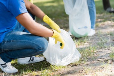 partial view of activists collecting rubbish in recycled bags, ecology concept clipart