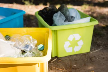 Geri dönüşüm amblemli kaplar, bulanık arka planda plastik atık dolu, ekoloji konsepti