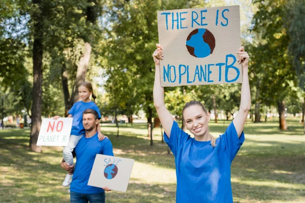 Happy Woman Holding Placard Planet Inscription Husband Daughter Posters Blurred — Stock Photo, Image