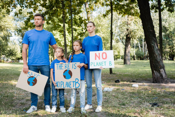 couple with two children holding posters with globe and no planet b inscription, ecology concept