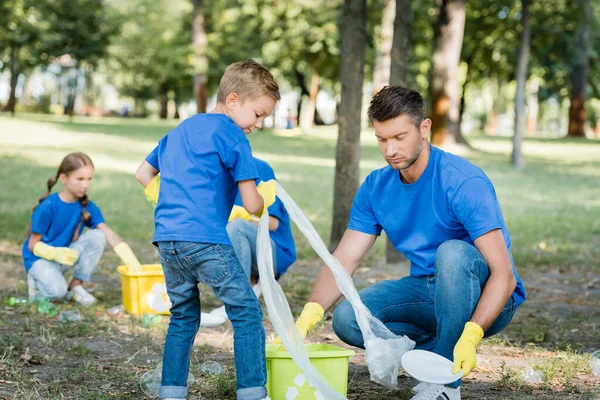 Padre Hijo Recogiendo Basura Plástica Cerca Madre Hija Sobre Fondo — Foto de Stock