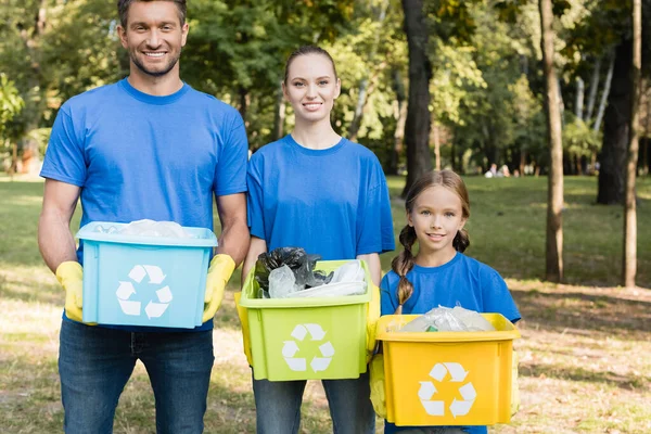 リサイクル記号付きの容器を持つ笑顔の家族プラスチック廃棄物生態学的概念でいっぱいです — ストック写真