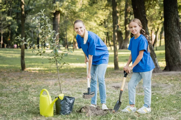 Mother Daughter Smiling Camera While Digging Ground Young Tree Watering — Stock Photo, Image