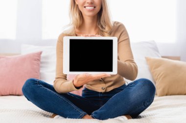 Yataktaki kadının ellerinde boş ekran olan dijital tabletin kırpılmış görüntüsü 