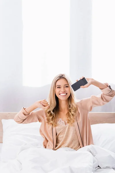 Mujer Sonriente Mostrando Teléfono Inteligente Con Pantalla Blanco Cama Casa — Foto de Stock