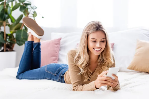 Fröhliche Frau Nutzt Smartphone Während Sie Hause Bett Liegt — Stockfoto