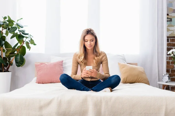 Ung Kvinna Med Korsade Ben Med Smartphone Sängen Hemma — Stockfoto