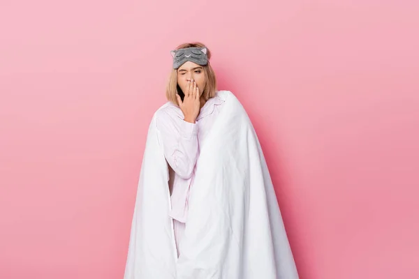 睡梦中女人穿着睡衣 毛毯打呵欠 背景是粉色的 — 图库照片