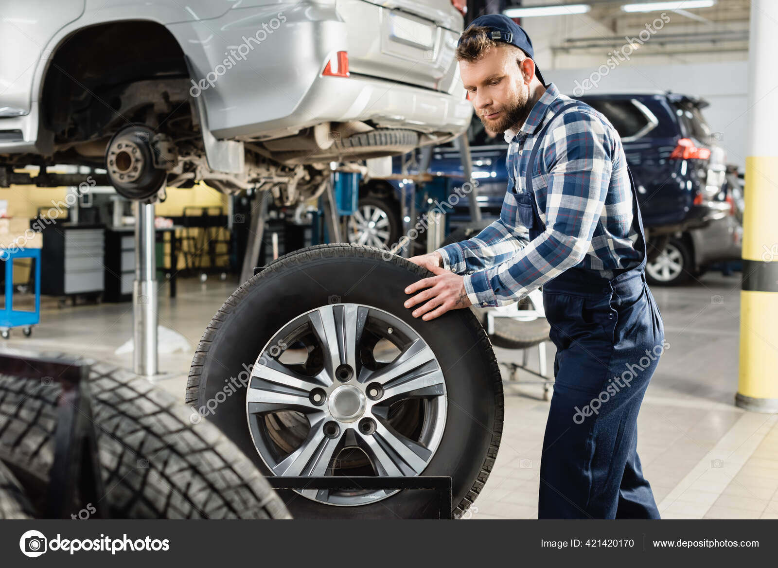 車のリフトで調達された車両の近くを移動する車輪全体の整備士 ストック写真 C Andrewlozovyi 車のリフトで調達された車両の近くを移動する車輪全体の整備士 ストック写真 C Andrewlozovyi