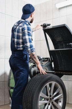 Atölyedeki dengeleme makinesinde tekeri kontrol eden tamirci