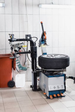 car wheel on tire replacement machine in workshop clipart