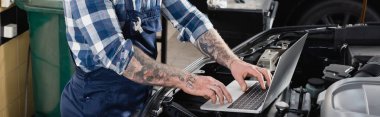 partial view of workman making diagnostic of car engine compartment with laptop, banner clipart