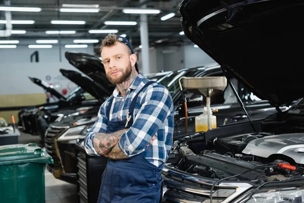 Tekniker Arbetskläder Tittar Kameran Stående Med Korsade Armar Nära Bilar — Stockfoto